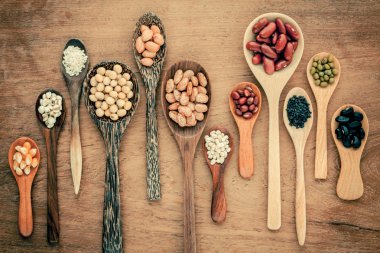 Assortment of beans and lentils in wooden spoon on teak wood bac