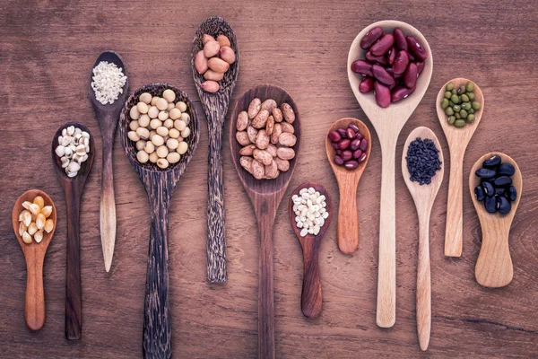 Surtido de frijoles y lentejas en cuchara de madera sobre bac de madera de teca — Foto de Stock