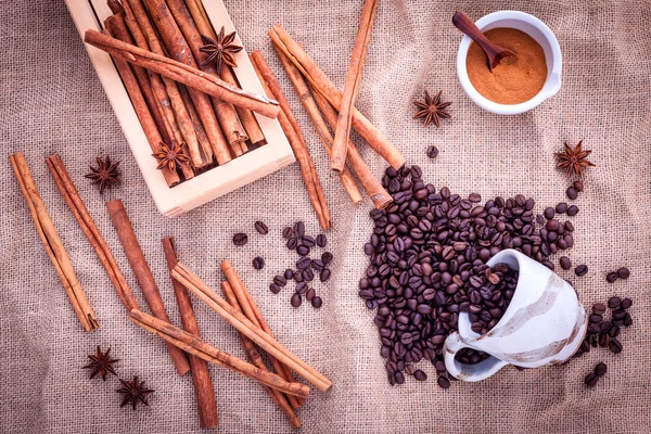 The Cup of coffee beans on the cloth sack with cinnamon sticks , — Stock Photo, Image