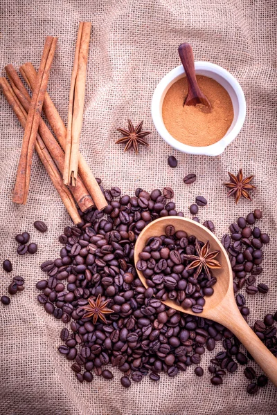 The Spoon of coffee beans on the cloth sack with cinnamon sticks — 图库照片