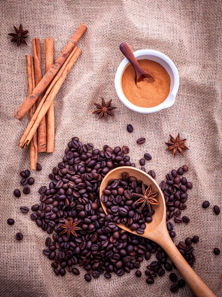 The Spoon of coffee beans on the cloth sack with cinnamon sticks — 图库照片