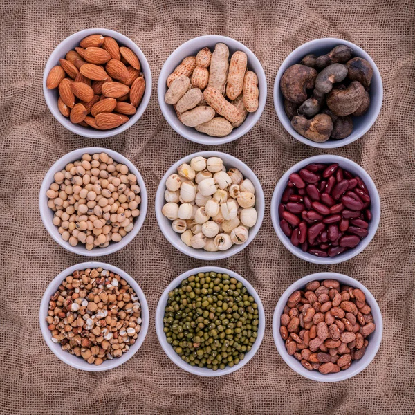 Frijoles mezclados, lentejas y nueces en el tazón blanco sobre tela marrón — Foto de Stock