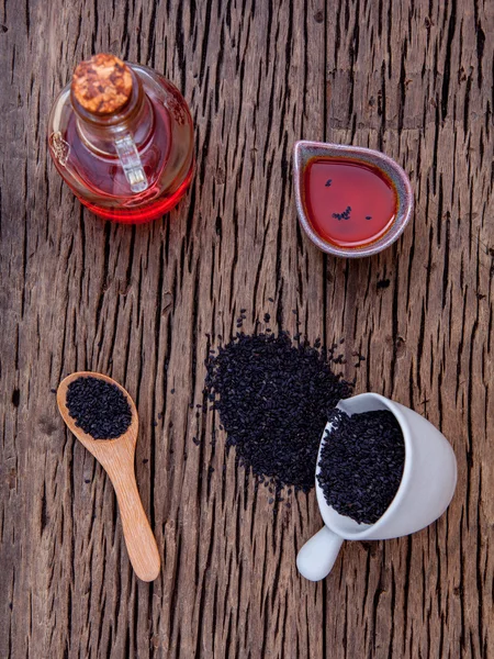 Black sesame oil and sesame seeds in white bowl set up