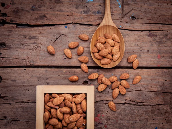 Almonds in wooden box and wooden spoon