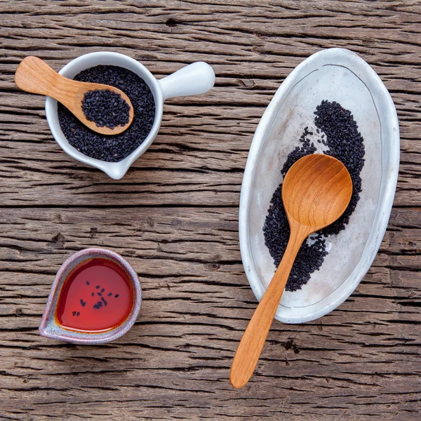 Black sesame oil and sesame seeds in white bowl set up