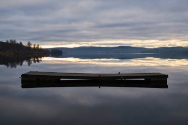 Akşamları göl kenarında boş bir ranza. Sakin su yüzeyi.