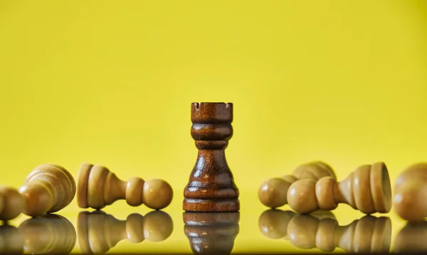 Rook winning the game, last chess piece standing on a yellow background. Victory, toughness and resilience concept.