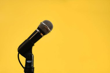 Sarı arkaplanda izole edilmiş mikrofon, iletişim konsepti