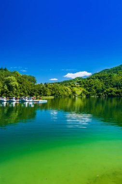 İnanılmaz yeşil Plivsko Gölü Jezero, Jajce, Bosna-Hersek, su yüzeyinde ahşap yansıması