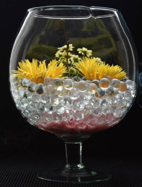 Çiçekli cam vazo ve siyah arka planda jel su topları.