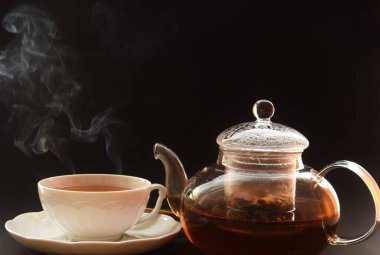 Çay yapraklı şeffaf çaydanlık ve çay fincanı. 