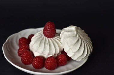 Siyah arka planda beyaz marşmelov ve taze ahududu. 