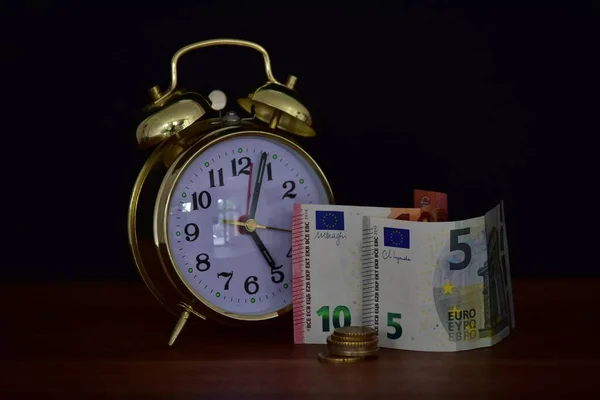 money and alarm clock on black background