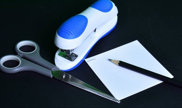 scissors stapler, ruler and simple pencil on black background 