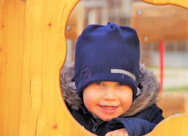 oğlan mavi şapkalı bir deliğe görünüyor