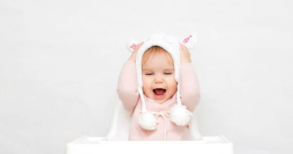 Portrait of a little girl child takes off or puts on a fluffy fur hat. Change of weather seasons, childrens clothing and accessories, discount sale — Stock Photo, Image