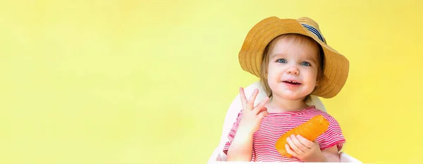 Holčička v slamáku drží mrkev. Dítě ukazuje tři prsty. Koncept vitamínů v mrkvi a šťavnaté léto — Stock fotografie