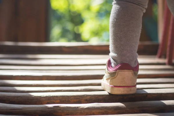 Cerca de los pequeños pies de niño al caminar en zapatillas blancas. Primeros pasos de verano sobre fondo bokeh verde. Enfoque selectivo y suave — Foto de Stock