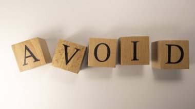 AVOID kelimesi ahşap küplerden yaratıldı. Tüketim ve alışveriş. Yakın plan..