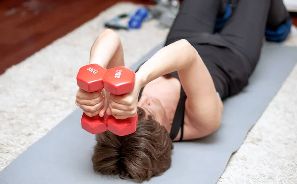 Ev fitness - halterli bir kadın yerde jimnastik yapıyor.