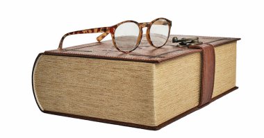 Boynuz çerçeveli gözlük kalın bir kitabın üzerinde yatıyor.
