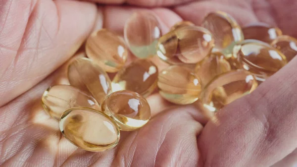 Omega-3 'lü kapsüller, bir adamın buruşuk avucunun üzerinde uzanıyor, beyaz arka planda izole edilmiş görüntü, makro