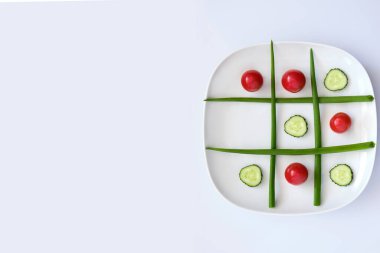 tic-tac-toe tabağı: yeşil soğan, kiraz domatesleri ve salatalık dilimleri, beyaz arka plan 