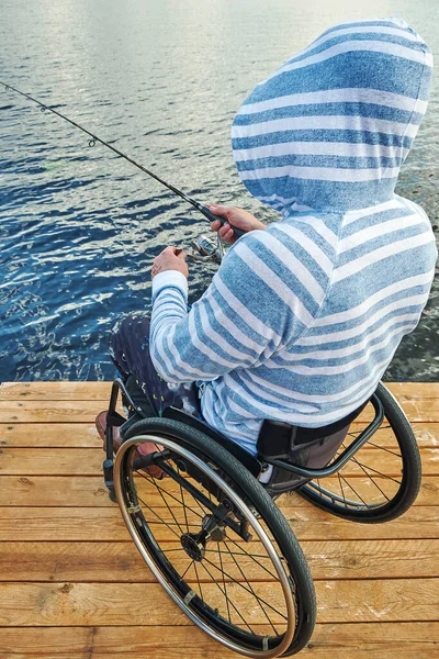 Disabile Sedia Rotelle Pesca Con Una Canna Spinning Foto Stock