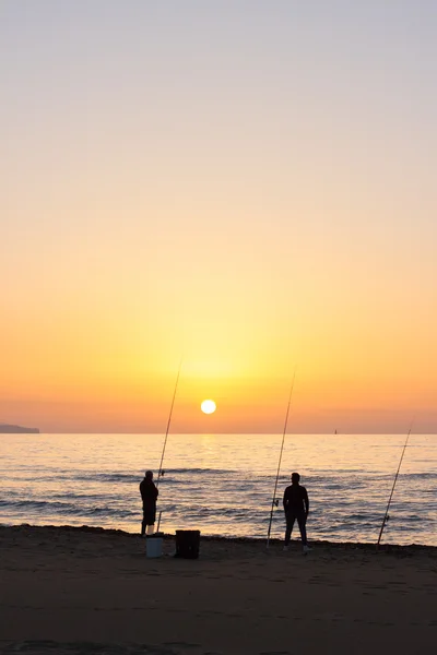 Muži při západu slunce na mořské pláži — Stock fotografie