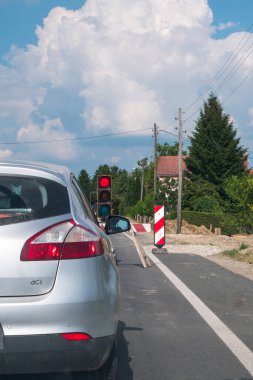 Yol çalışmaları devam ediyor. Araba yol inşaatı trafik lambasının önünde duruyor. Trafik ışığı kırmızı..