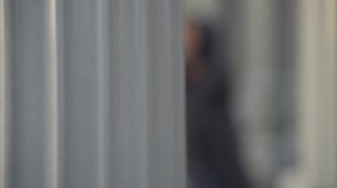 Büyük bina sütunları arasında elbise giyen Asyalı Müslüman bir kadının Urban Light 'taki görüntüsü, Chris Burden' ın Los Angeles Sanat Müzesi 'nde yaptığı büyük ölçekli bir heykel..