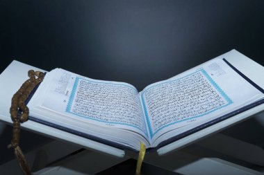 Kitap istirahatı üzerine kutsal Kur 'an. Ahşap arka planda izole edilmiş. İnsanlar geceleri kitap okuyor..