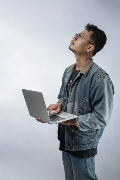 portrait of an Asian man confusing and thinking while working on a laptop isolated in white