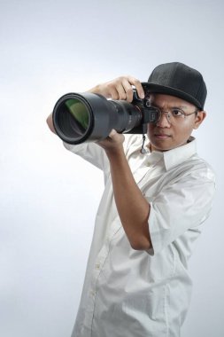 The photographer looks through the viewfinder while shooting with the professional camera isolated in white background.