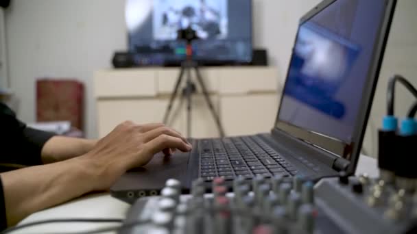 Videobeelden Een Man Typen Een Laptop Met Audio Mixer Controller — Stockvideo