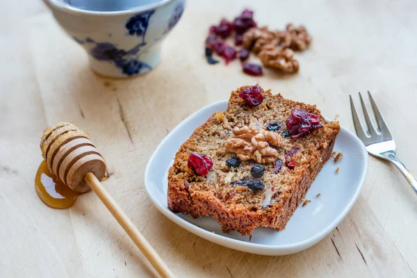 A slice of vegan cake with super fruits, nuts and honey on wooden table