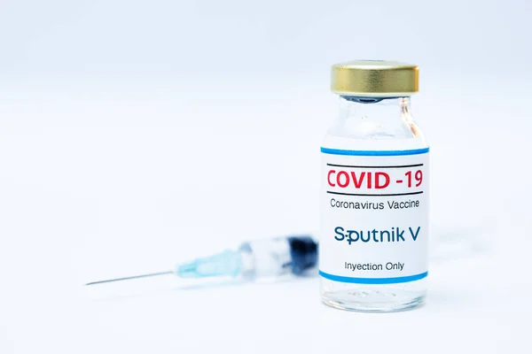 Flacone di vaccino coronavirus con logo Sputnik V e sfondo della siringa. — Foto Stock
