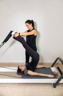 Pilates hocasıyla egzersiz yapan bir kadın..