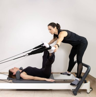 Pilates hocasıyla egzersiz yapan bir kadın..