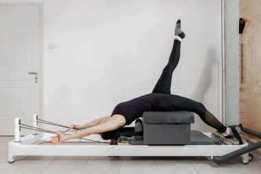 Islah olmuş bir yatakta pilates egzersizi yapan bir kadın..