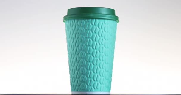 緑色の紙コーヒーカップが回転 熱い飲み物のための使い捨てカップ コーヒー豆のエンボス加工 エスプレッソ カプチーノを飲んで — ストック動画