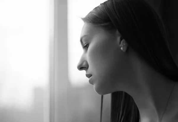 Imagen de una mujer hermosa mirando por una ventana. Foc selectivo — Foto de Stock