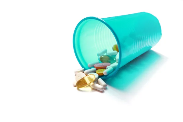 Image of different pills spilling out of a plastic glass — Stock Photo, Image