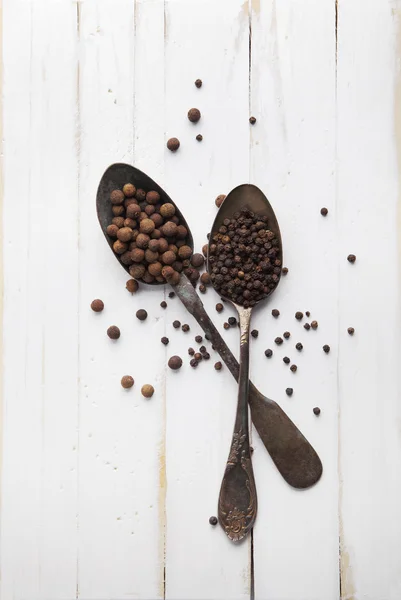 Image of spoons full of black peppercorn and allspice on wooden — Stock Photo, Image