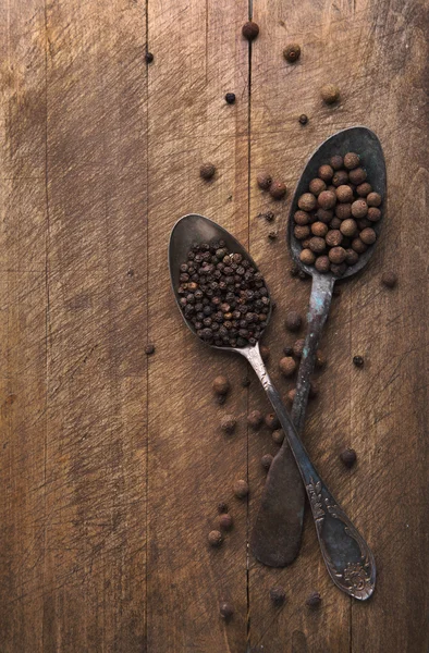 Image of spoons full of black peppercorn and allspice on wooden — Stock Photo, Image