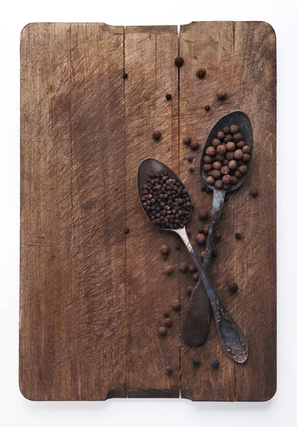 Image of spoons full of black peppercorn and allspice on wooden — Stock Photo, Image