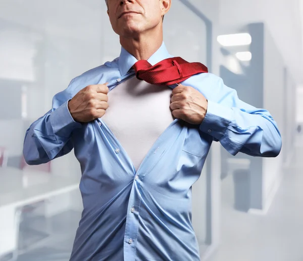 Superhelden. Reifer Geschäftsmann reißt im Büro sein Hemd vom Leib — Stockfoto