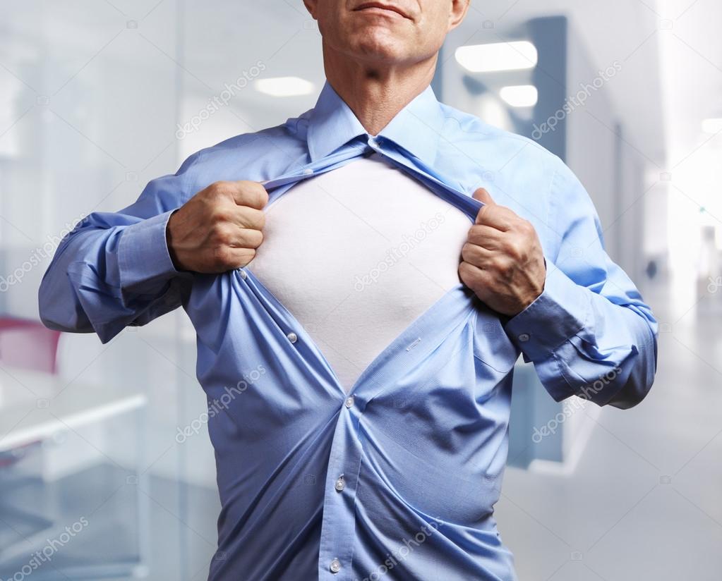 Superhero. Mature businessman tearing his shirt off over office 