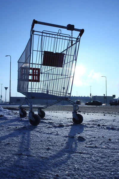 Bild eines leeren Einkaufswagens auf einem leeren Parkplatz in der Nähe eines riesigen Ladens — Stockfoto