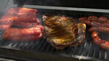 Domuz pirzolası, kırmızı biber ve İspanyol sucuğu bir evin bahçesinde ızgarada kızartılıyor. Aşçı lezzetli ızgara etle barbekü yapıyor.